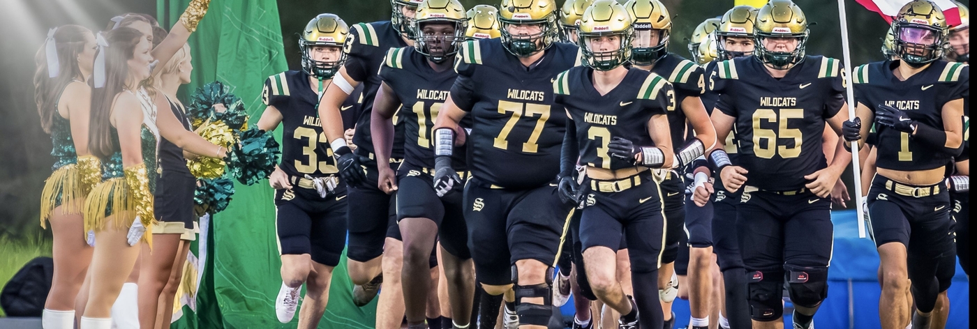 Image of Football players running on to the Silliman Football Field